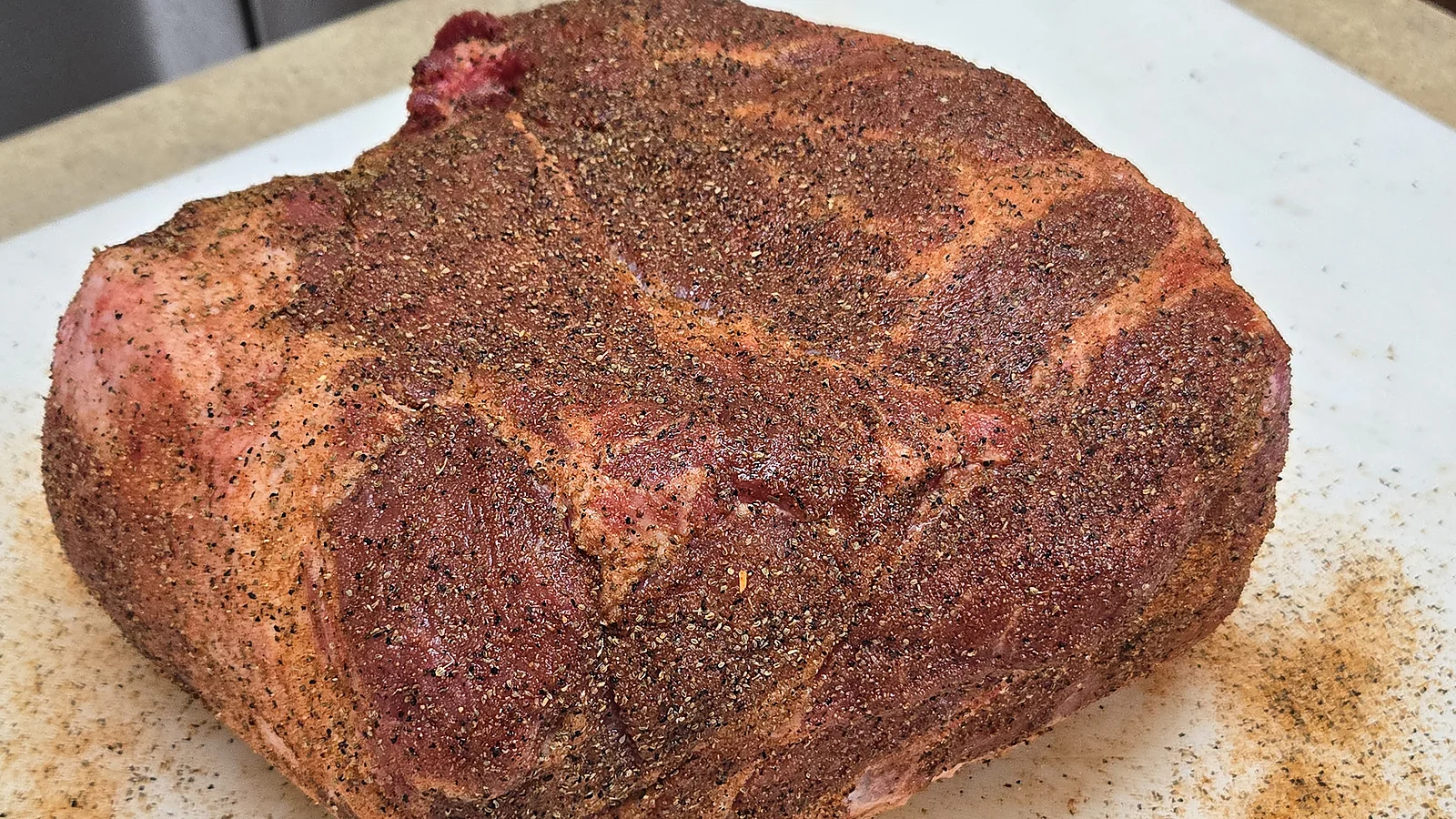 Seasoned pork butt resting on the cutting board