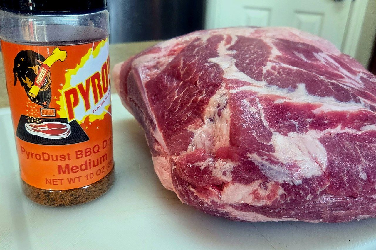 Raw pork butt next to PyroDust BBQ Dry Rub, showing the starting point before browning.