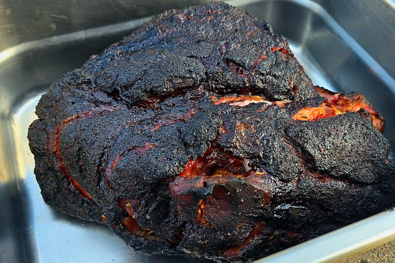 Finished smoked pork butt resting, showing dark bark and rendered exterior.
