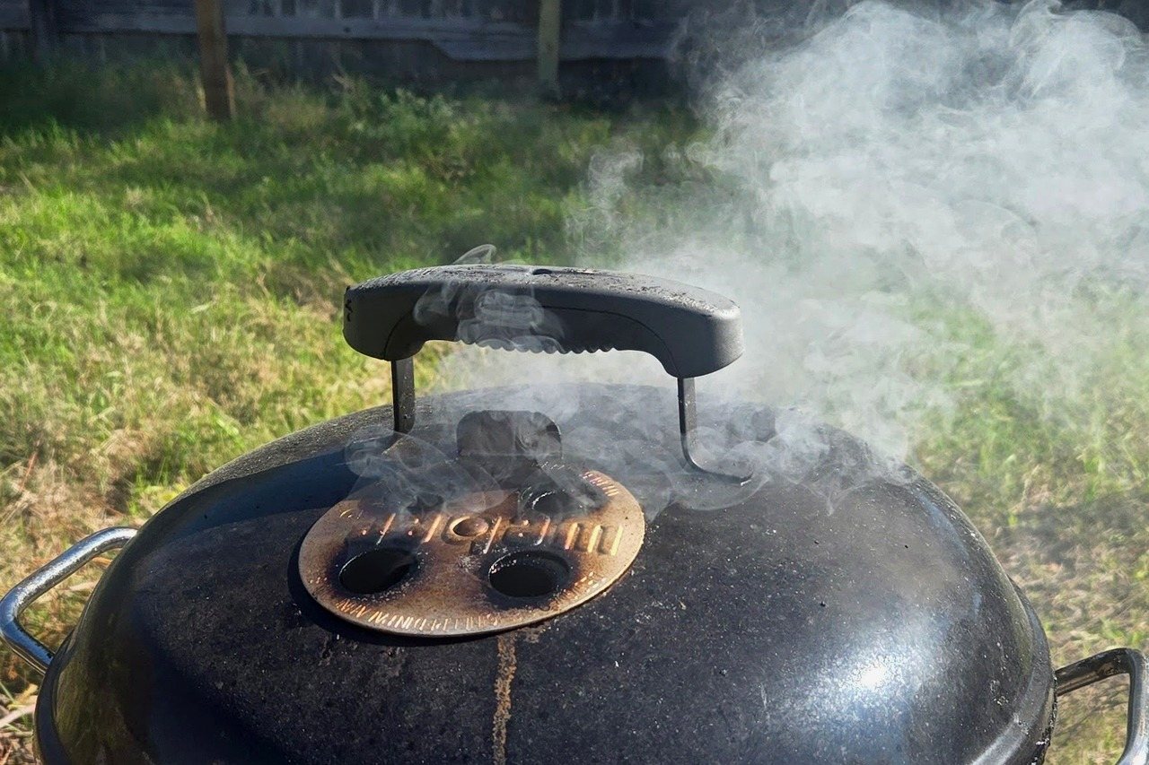 Thick white smoke pouring from a smoker vent.