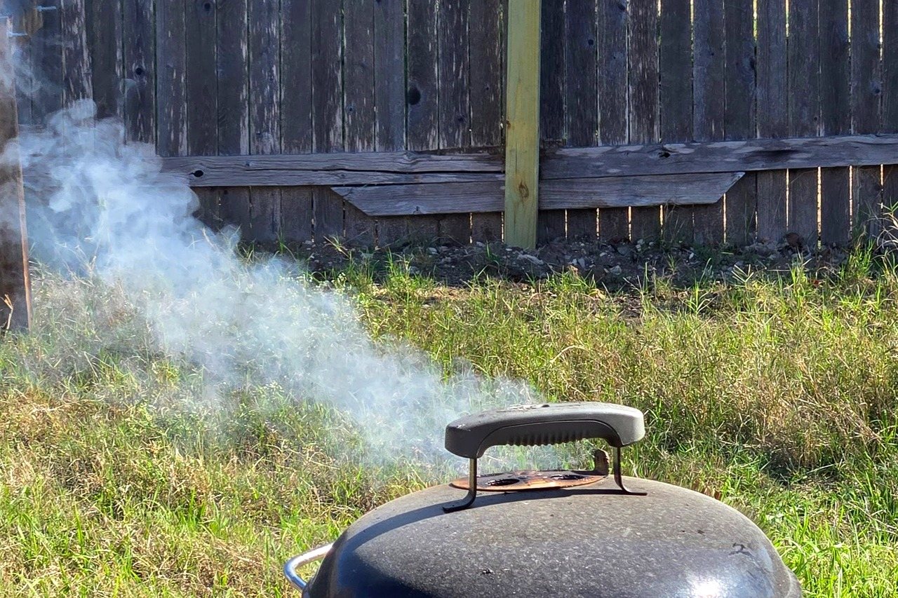 Moderate white smoke rising from a smoker, not as dense as thick dirty smoke.