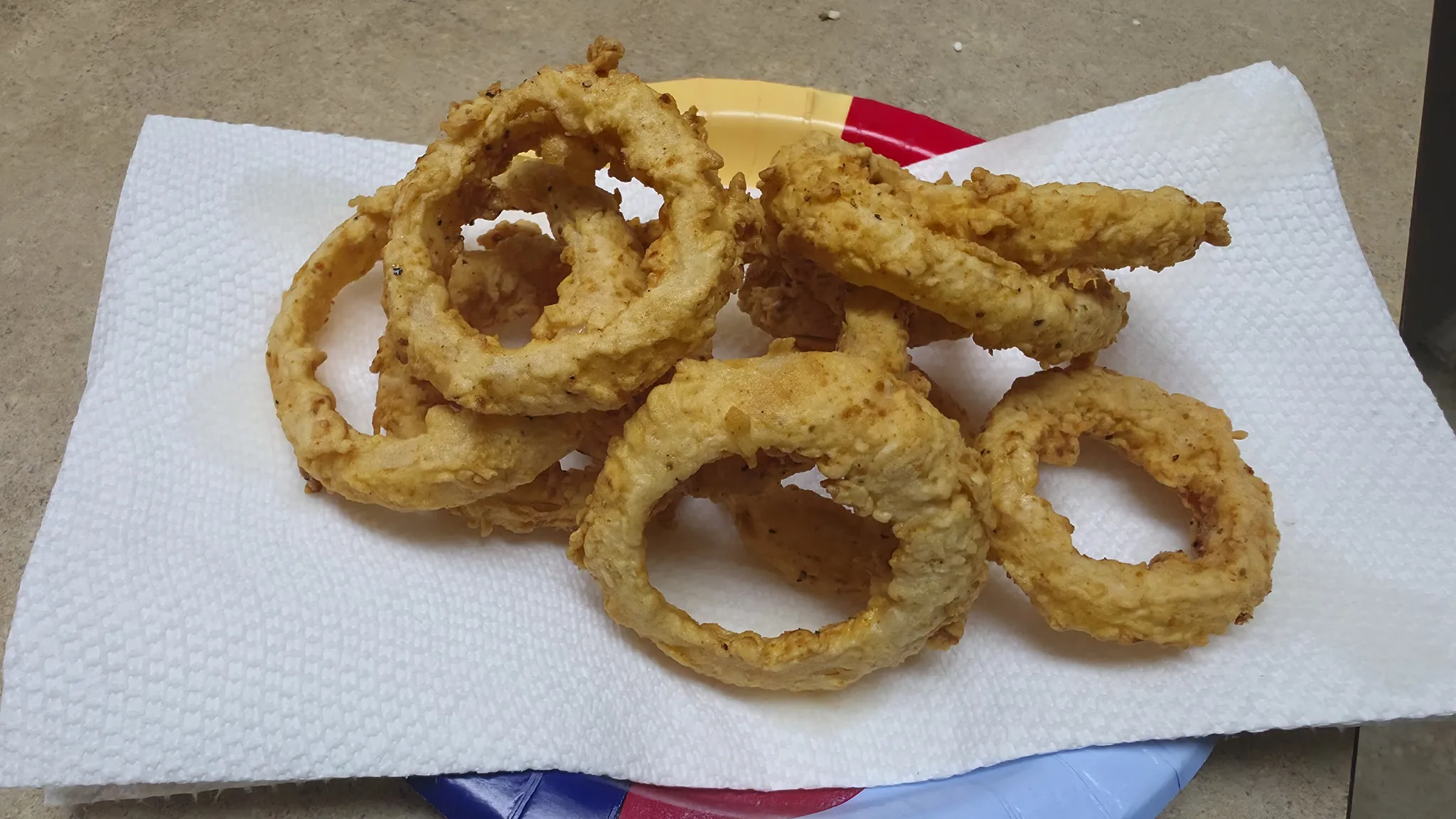 Onion rings after the first fry with a firm, light golden coating